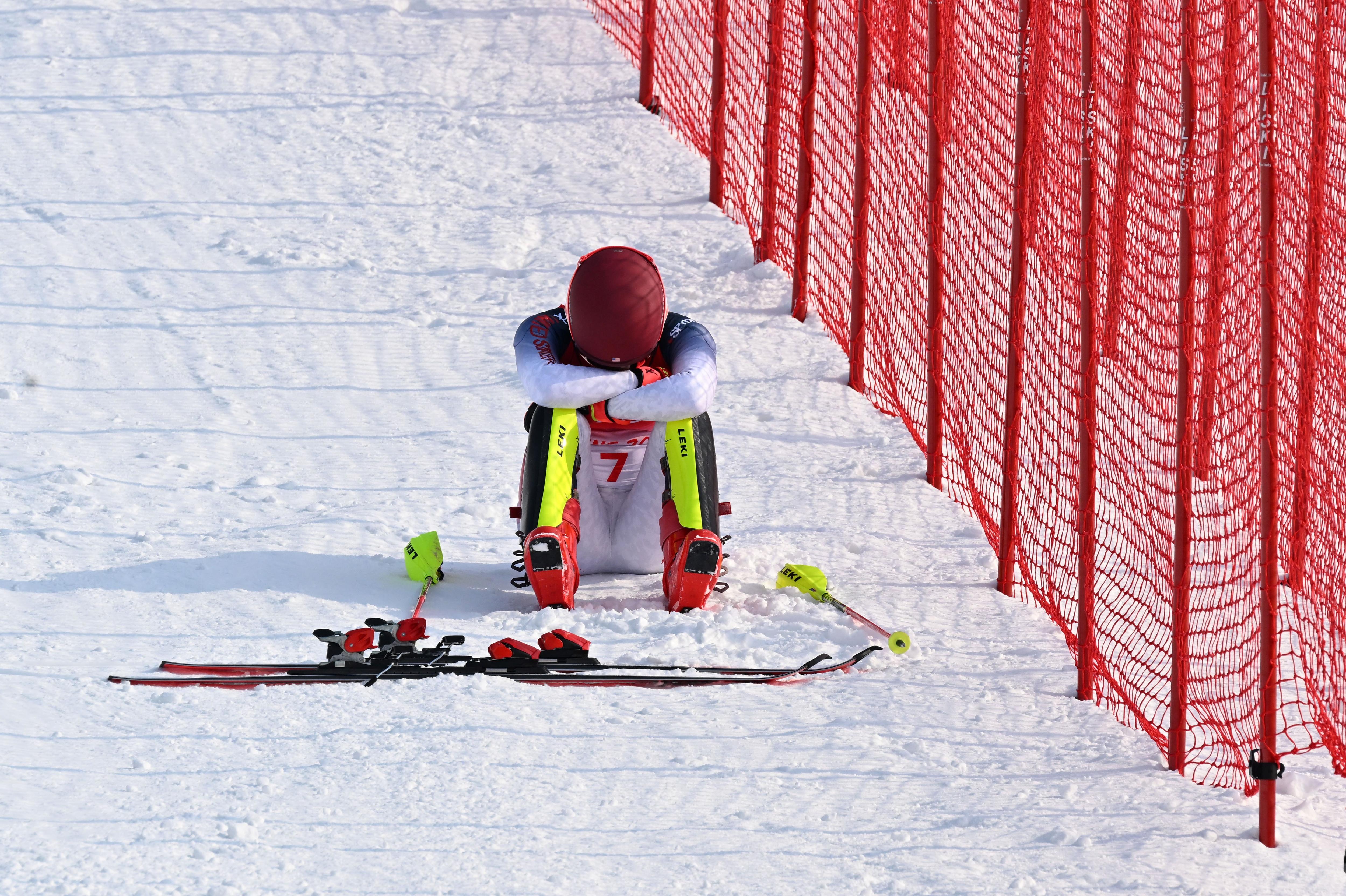 一名冬季运动员坐在在雪地里抱着头